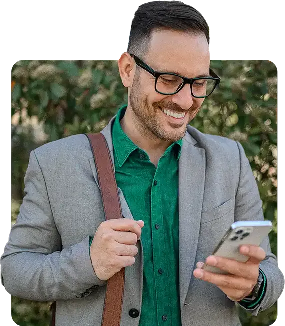 Homem de negócios sorridente, olhando para o celular enquanto simula um crédito para CLT no app Konsi